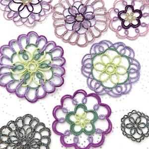 K&ouml;nnte beinhalten: Eine Sammlung handgefertigter Spitzendeckchen in verschiedenen floralen Designs. Die Deckchen weisen Farbt&ouml;ne von Lila, Gr&uuml;n und Gelb auf, mit komplizierten Mustern und filigranen Details. Sie sind auf einer wei&szlig;en Oberfl&auml;che angeordnet.