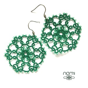 May include: A pair of green crocheted earrings with silver hooks. The earrings are round and feature a delicate, intricate design.