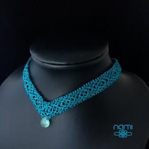 May include: Teal blue crocheted choker necklace with a teal blue gemstone pendant.