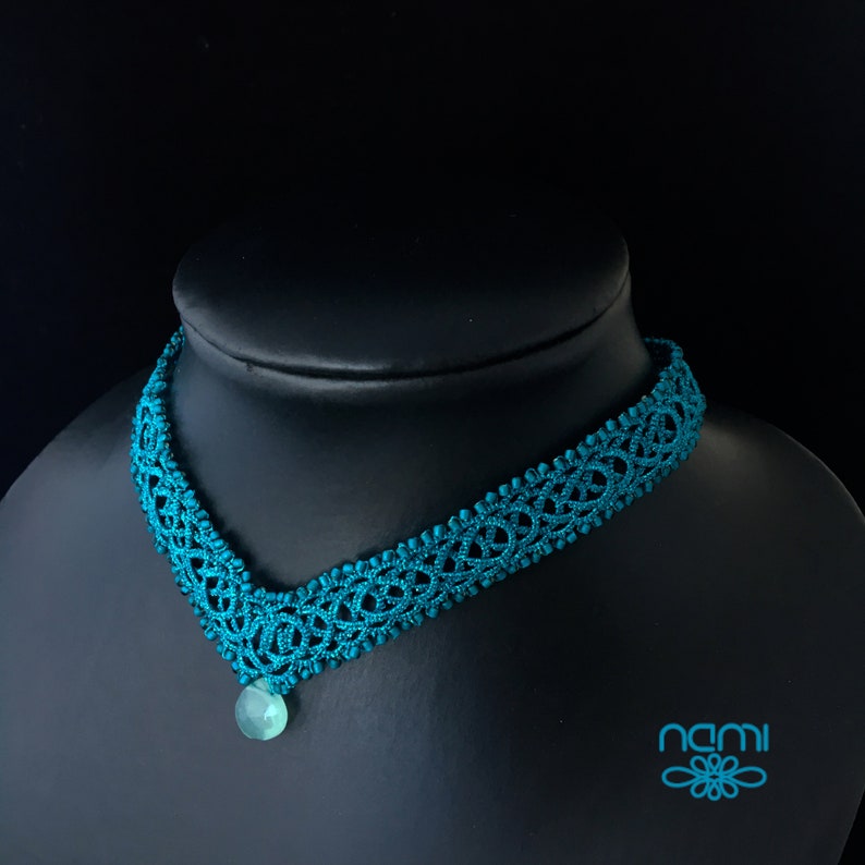 May include: Teal blue crocheted choker necklace with a teal blue gemstone pendant.