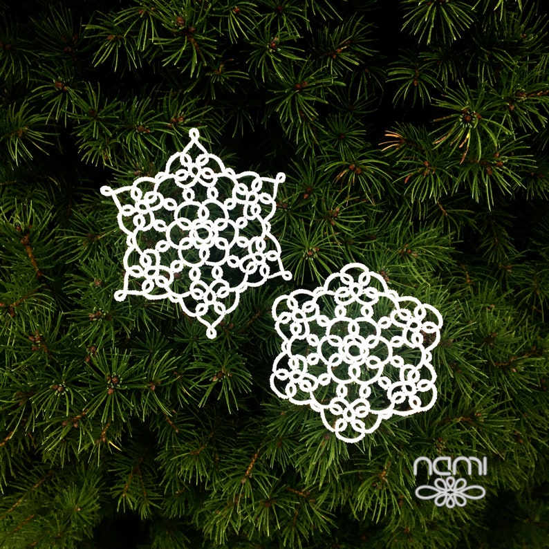 May include: Two white crocheted snowflakes on a green pine tree background.