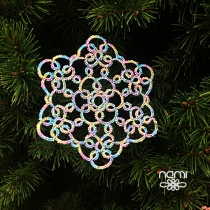 May include: A colorful snowflake ornament made of delicate crocheted thread. The snowflake is a light blue, pink, and yellow color and has a sparkly finish.