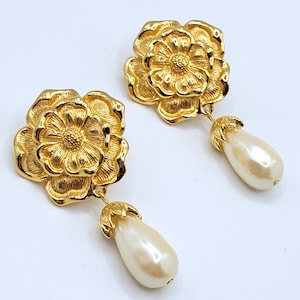 May include: Gold tone flower drop earrings with a faux pearl dangle.