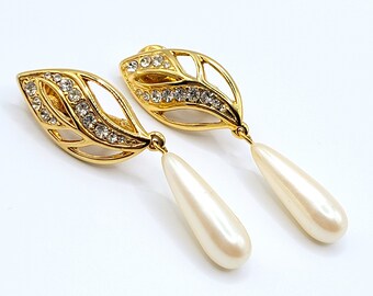 May include: A pair of gold tone earrings with a leaf design and clear rhinestones. Each earring has a pearlescent drop.