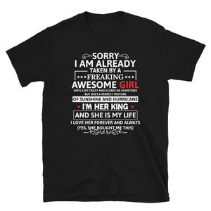 Pode incluir: T-shirt preto com texto branco. O texto diz "SORRY I AM ALREADY TAKEN BY A FREAKING AWESOME GIRL". O texto continua com "I'M HER KING AND SHE IS MY LIFE". Uma ideia de presente romântica.