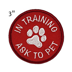 May include: A round, red embroidered patch, 3 inches in diameter, with white text and a paw print. The text reads "IN TRAINING ASK TO PET".