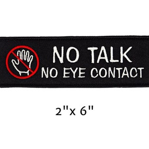 May include: Black rectangular patch with white text reading "NO TALK NO EYE CONTACT". A red circle with a hand symbol crossed out is on the left. The patch measures 2" x 6".
