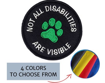 May include: A circular black embroidered patch with white text reading "NOT ALL DISABILITIES ARE VISIBLE". A green paw print is in the centre. A smaller circle shows four colour options. The text "4 COLOURS TO CHOOSE FROM" is below.