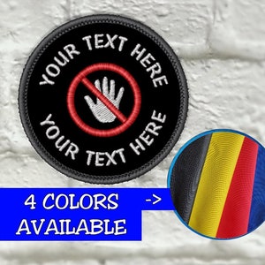 May include: A round black patch with the text "YOUR TEXT HERE" and a red "no entry" symbol over a white hand. The patch has a black border and is set against a white brick wall. The image also shows a blue rectangle with the text "4 COLORS AVAILABLE" and a color swatch.