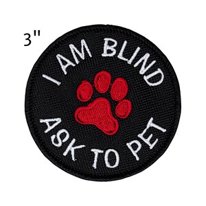 May include: A 3-inch round black patch with white embroidered text that reads "I AM BLIND ASK TO PET". A red paw print is in the center. This patch is designed for pets.