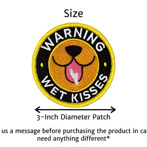 Puede incluir: Parche bordado con un dise&ntilde;o de cara de perro. El parche es redondo, de 7,6 cm de di&aacute;metro, y presenta el texto "WARNING WET KISSES" alrededor de la cara del perro. La cara del perro es marr&oacute;n con una lengua rosa.