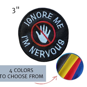 May include: A 3-inch round black embroidered patch with the words "IGNORE ME I'M NERVOUS" in white. A red circle with a white hand crossed out is in the center. The image also shows a color palette with four color options.