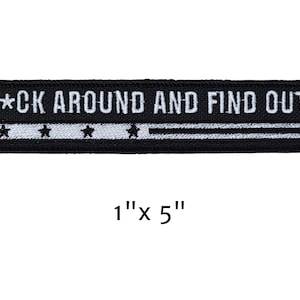 May include: Black embroidered patch with the text "F*CK AROUND AND FIND OUT" in white. The patch is rectangular, measuring 1 inch by 5 inches, with a white stripe and star design.