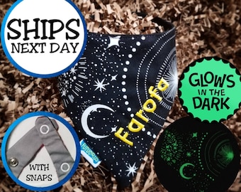 Puede incluir: Bandana negra para perros con un diseño celestial con estrellas, lunas y fuegos artificiales. La palabra "Farofa" está bordada en amarillo. La bandana tiene broches y brilla en la oscuridad. El texto "Ships Next Day" también es visible.