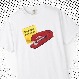 May include: White t-shirt with a red stapler design, the name "Milton", and a yellow sticky note saying "Excuse me, I believe you have my stapler...". The design is a reference to a popular film.