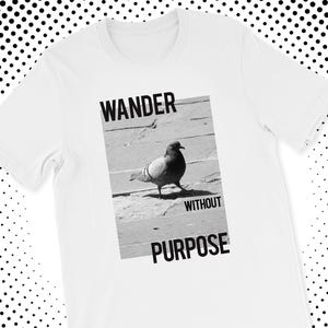 May include: White t-shirt featuring a black and white image of a pigeon walking on a brick surface. The image is framed by the words "WANDER WITHOUT PURPOSE" in bold, black font. The shirt is made of a soft, comfortable material.