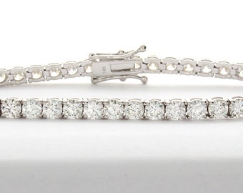 May include: A silver tennis bracelet with a row of round, clear diamonds.