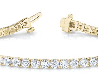 Puede incluir: Un brazalete de tenis de oro con una fila de diamantes redondos.