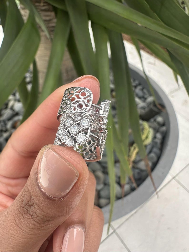 Puede incluir: Un anillo de plata con un dise&ntilde;o delicado e intrincado que presenta un patr&oacute;n de celos&iacute;a y piedras transparentes brillantes.