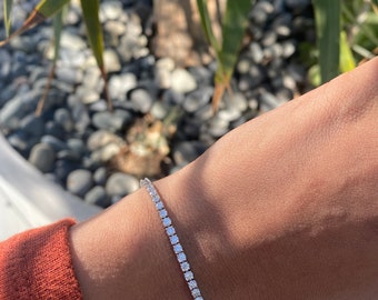 Könnte beinhalten: Ein silbernes Tennisarmband mit kleinen, klaren Steinen.