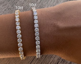 Puede incluir: Dos pulseras de tenis con diamantes de 10 ct, una en oro y otra en plata, en la muñeca de una persona.