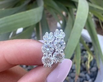 May include: A pair of silver hoop earrings with a row of three round, clear diamonds on each hoop.