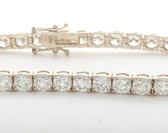 May include: A silver tennis bracelet with a row of round, clear stones.