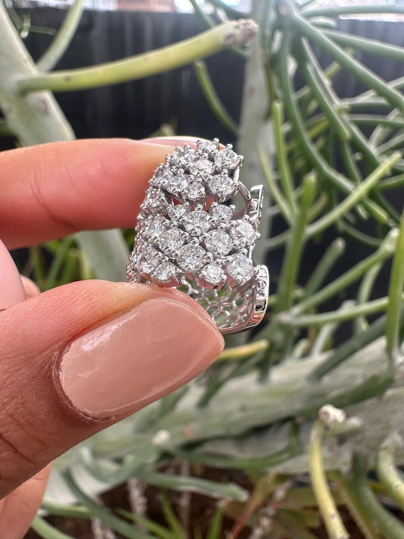 Puede incluir: Un anillo de plata con un gran racimo de diamantes brillantes engastados en un dise&ntilde;o delicado e intrincado.