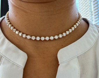 May include: A gold chain necklace with a row of round, clear diamonds.