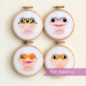 May include: Four cross-stitch patterns of leopard geckos in embroidery hoops. The geckos have different expressions and colours. The text "PDF Patterns" is at the bottom of the image.