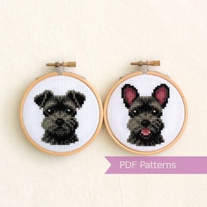 May include: Two framed cross-stitch patterns of black miniature schnauzers. The schnauzers are both looking at the viewer. The pattern on the left has a more serious expression, while the pattern on the right has a more playful expression. The text "PDF Patterns" is printed on a purple banner below the patterns.