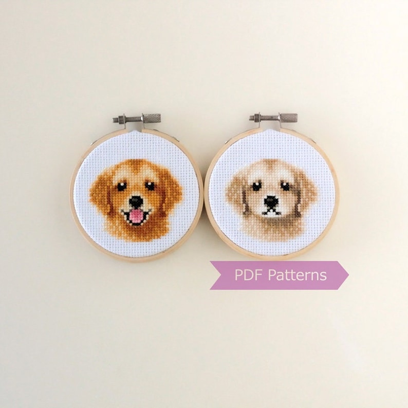 May include: Two cross-stitch patterns of golden retriever dog heads in embroidery hoops. The patterns are available as PDF downloads.