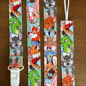 May include: A fabric pacifier clip featuring a repeating pattern of colorful cartoon animal characters with pacifiers on a light blue background. The strap includes a white plastic clip at one end and a white fabric loop at the other end.