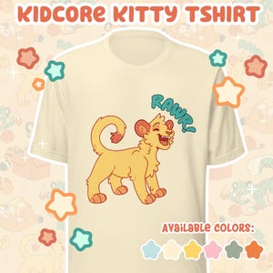 May include: Cream-colored t-shirt with a cartoon lion cub illustration. The lion cub is yellow with a red-orange mane and paws, and the word "RAWR!" is written above it in blue. The shirt has the text "KIDCORE KITTY TSHIRT" at the top.