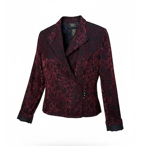 May include: A long-sleeved blazer in deep burgundy and black with a floral brocade pattern. The jacket features a notched lapel, a single-breasted front closure with three small buttons, and folded cuffs. The interior is lined in solid black fabric.