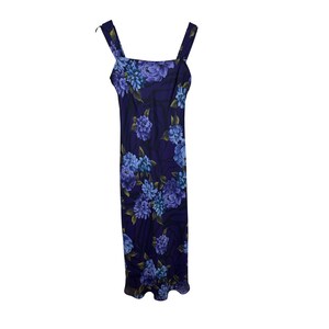 May include: A sleeveless, floor-length dress with a floral pattern. The dress features a dark blue background with large blue and purple flowers. It has a square neckline and wide straps.