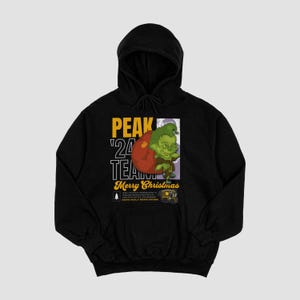 May include: Black hooded sweatshirt with a graphic of a green creature holding a red ball. The text "PEAK '24 TEAM Merry Christmas" is printed on the front of the sweatshirt.