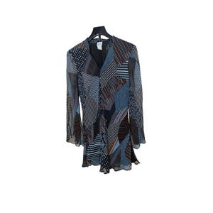 May include: A long-sleeved dress with a V-neck and a patchwork design. The dress features a mix of blue, brown, and white geometric patterns. The sleeves are flared, and the dress hangs on a black hanger against a white background.