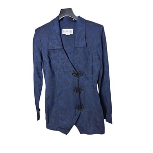 Puede incluir: Blazer azul marino con estampado floral y mangas largas. El blazer presenta un cierre asimétrico único con tres botones negros decorativos. La etiqueta dice "RAMPAGE".