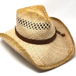May include: A light brown straw cowboy hat with a brown leather band. The hat has a woven design and a wide brim.