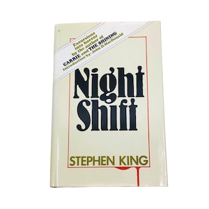 May include: A hardcover book titled "Night Shift" by Stephen King. The cover is cream-colored with a red border and features the title in large, black, bold letters. The book also includes text about the author and introduction.