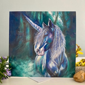 May include: A square greeting card featuring a painting of a unicorn in a forest. The unicorn has a blue-black coat and a white mane and horn. The background is a dark forest with an owl.