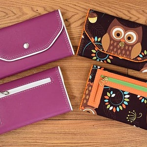 May include: Four different wallets, two are purple with white stitching and two are black with an owl print and orange stitching.