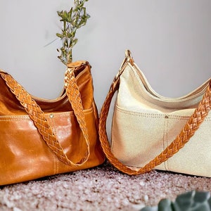 May include: Two brown leather tote bags with braided straps. One bag is brown leather and the other is a light beige canvas.