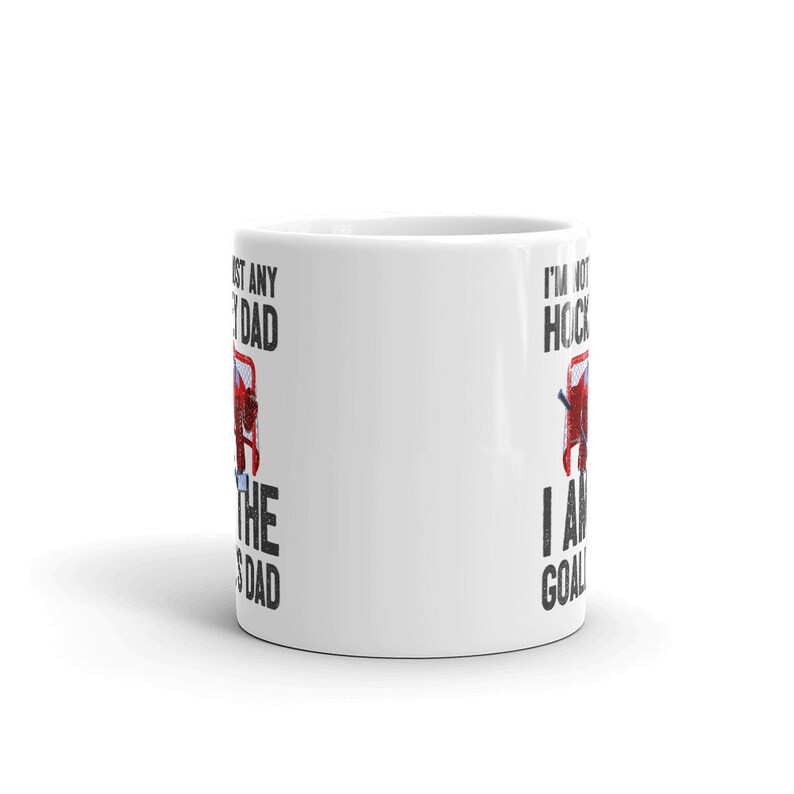 May include: White ceramic mug with the text "I'm not just any dad, I am the goalie's dad" in black and red. The mug features a hockey net graphic. A perfect gift for a hockey dad.