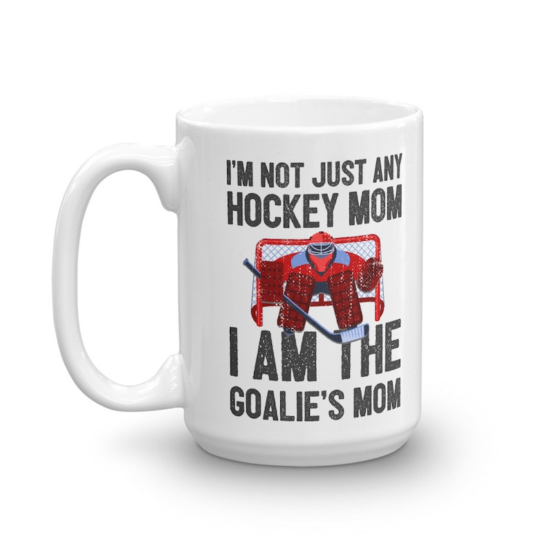 May include: White ceramic coffee mug with a black and white graphic that reads "I'm not just any hockey mom I am the goalie's mom". The graphic features a hockey goalie in a red and blue uniform standing in a goal.