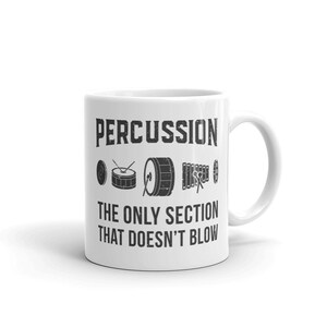 Può includere: Tazza in ceramica bianca con una grafica nera che recita "PERCUSSION THE ONLY SECTION THAT DOESN'T BLOW". La grafica include un set di strumenti a percussione, tra cui una batteria, un piatto e uno xilofono.