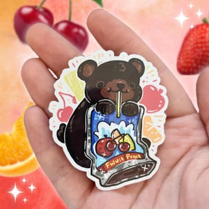 May include: A sticker featuring a cartoon bear drinking from a fruit punch pouch. The bear is brown with a light brown snout and ears. The fruit punch pouch is blue with cherry and fruit illustrations. The text "Fruit Punch" is visible.