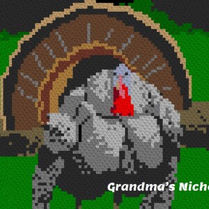 Puede incluir: Un pavo de ganchillo gris y blanco con una papada roja y una cola en forma de abanico de ganchillo marrón. El pavo está sentado en un tronco marrón con hierba verde en el fondo. El texto "Grandma's Niche ©" está en la esquina inferior derecha de la imagen.