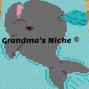 May include: A crochet blanket featuring a pixelated gray dolphin design on a light blue background. The dolphin has a small pink detail on its head and a dark eye. The text Grandma's Niche is printed in black across the center of the blanket.